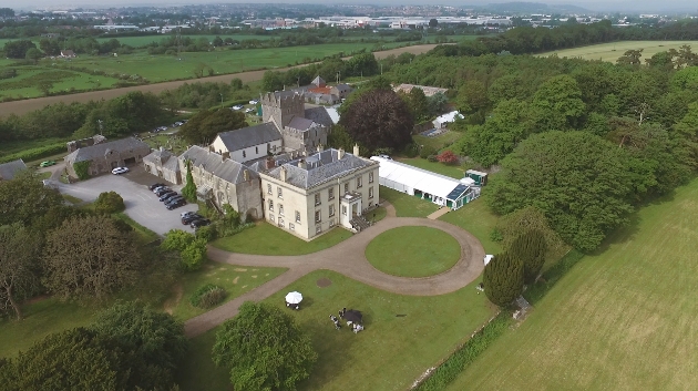 A birds eye view of a grand manor house surrounded by countryside