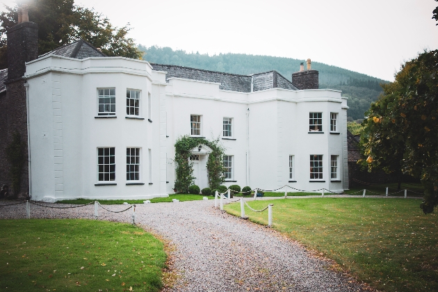 A large white manor with mountains in the background