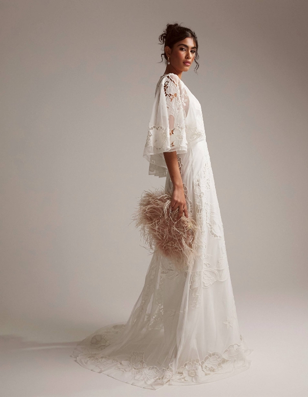 model in lace gown with long cape-style sleeves