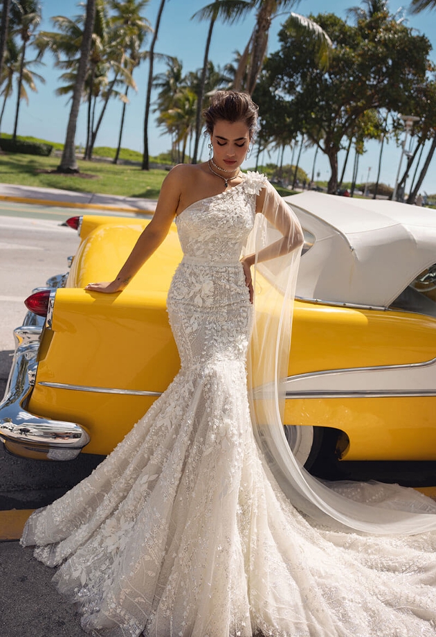 A woman wearing a wedding dress leaning on a yellow car