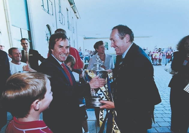 A man smiling at the camera while accepting a trophy 