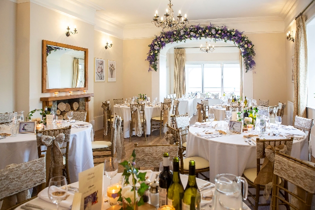 A light filled room decorated with round tables and flowers