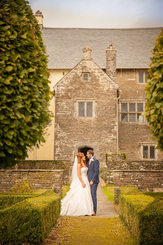 A bride and groom standing in front of a brick building