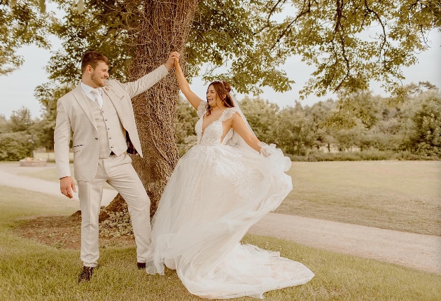 A bride and groom dancing in front of a tree