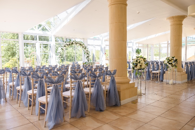 A light-filled room decorated with chairs and flowers