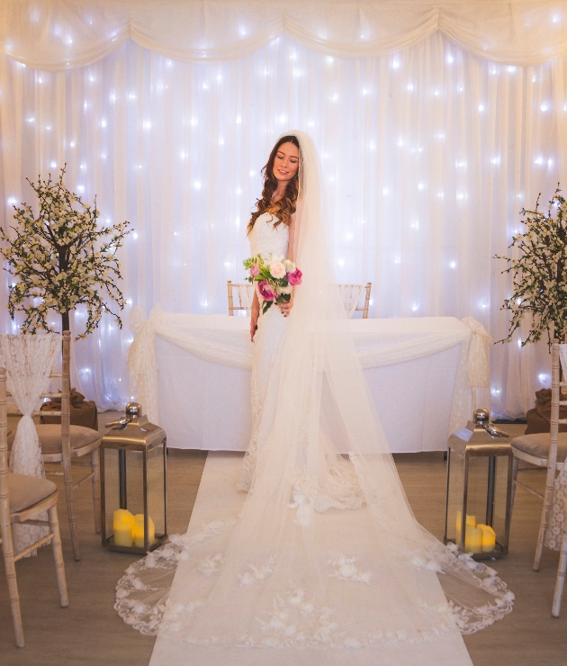 A bride standing in front of a fairylight curtain