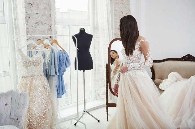 A woman trying on a wedding dress and admiring herself in the mirror