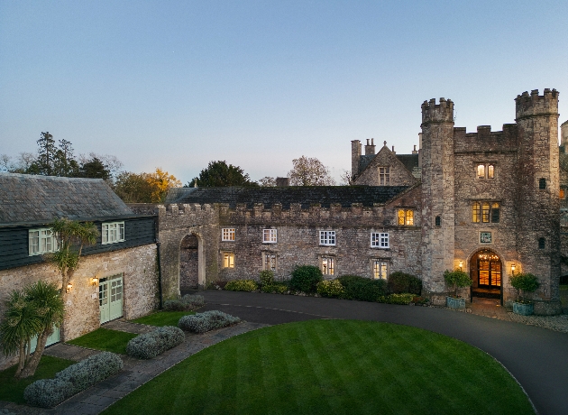 The exterior of a large manor house as the sun is setting