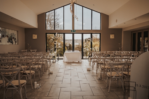 A large room with several windows and doors at the end of an aisle decorated with flowers