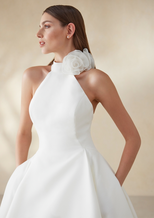 A woman wearing a high-neck sleek wedding dress with pockets