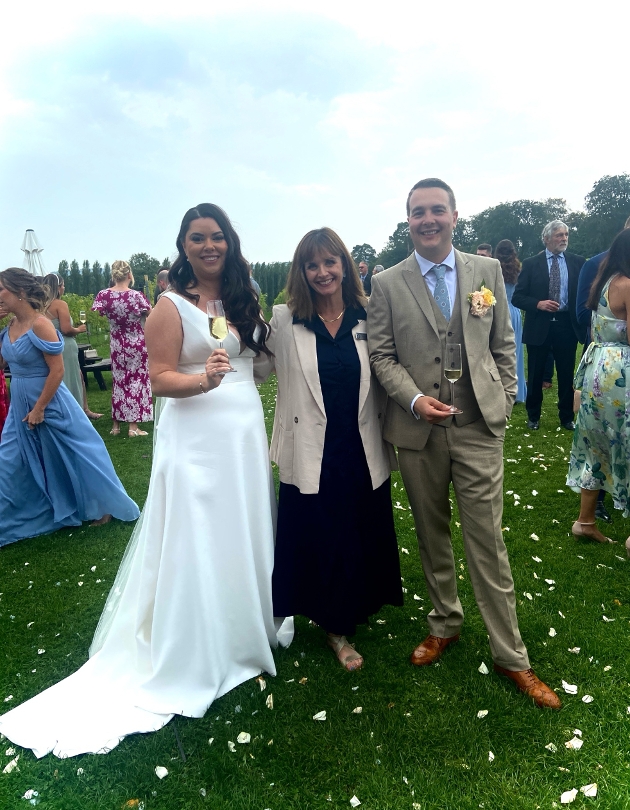 A bride and groom standing alongside celebrant Claire Cousin