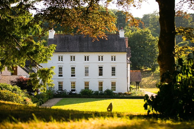 A large white building surrounded by manicured gardens and trees