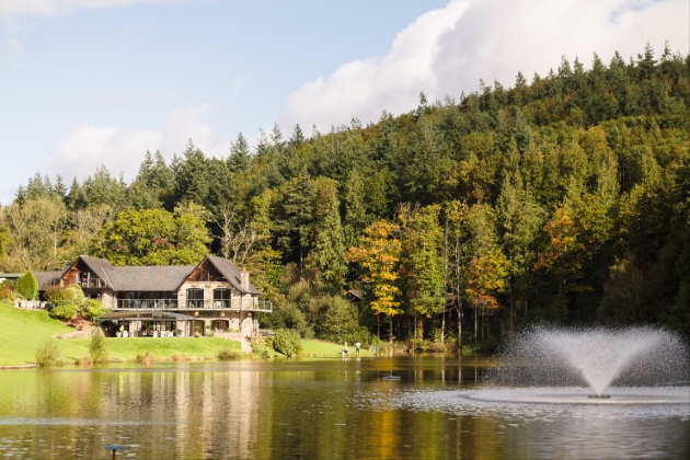 A stone building overlooking a lake with a forest behind it