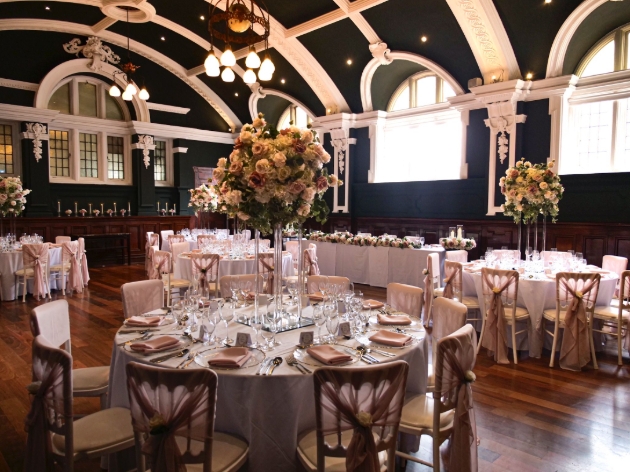 A dark room filled with white round tables that are decorated with flowers