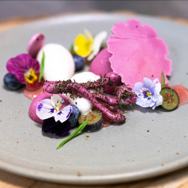 A dish made up of flowers and pink sauce